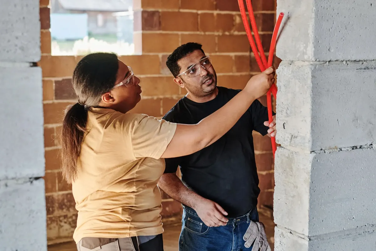 Two tradespeople checking cable runs on a building site