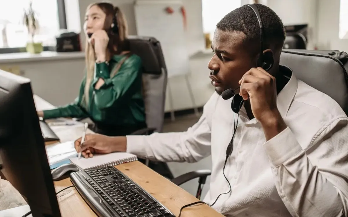 Two people answering business calls on headsets at their desks